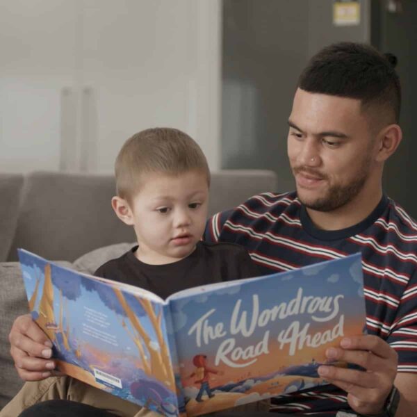 Father reading a book to his kid from the Redkite Book Club service